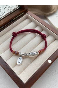 Détail du bracelet chat porte-bonheur tressé rouge avec breloques en argent S999 en boîte