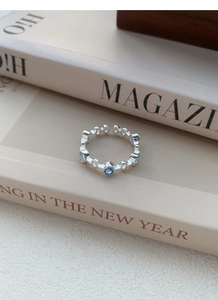 Close-up of adjustable silver ring with light blue zircons set between book pages