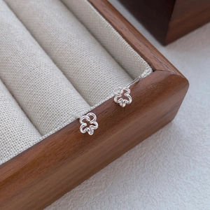 Élégantes boucles d'oreilles fleurs creuses en argent S999 sur une boîte à bijoux en bois