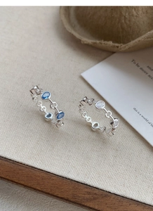 Detailed view of silver chain rings featuring oval blue and white zircon gemstones