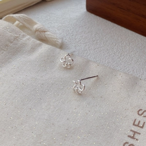 Boucles d'oreilles fleur évidée en argent sterling S999 sur pochette à bijoux en lin