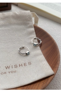 Détail des boucles d'oreilles en argent S999 avec zircon bleu sur fond de lin
