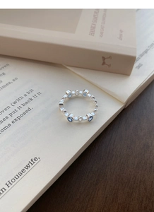 Detailed view of silver ring with light blue zircon stones placed on an open book