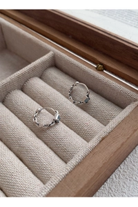 Détail de boucles d'oreilles en argent avec zircon bleu carré sur support en lin