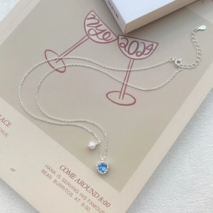 Halskette aus S925 Silber mit blauem Herz Zirkon und Süßwasserperle auf beigem Hintergrund