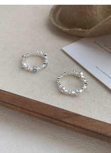 Detail of S925 silver rings with blue and clear zircon on a textured beige fabric background