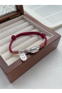Détail du bracelet en corde rouge avec breloque chat en argent S999 sur boîte à bijoux