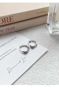 Détail des boucles d'oreilles en argent S925 avec zircon bleu sur carte artistique