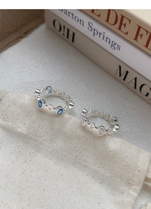 Detail of S925 silver link rings with oval blue and white zircon on a cotton bag