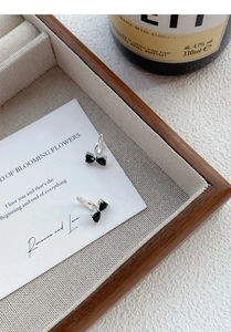 Detailed view of silver bow earrings with black pear-shaped zircons on a jewelry tray