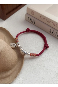 Détail du bracelet en corde tressée rouge avec perle de chat en argent et étiquette