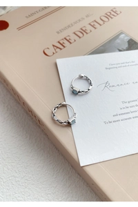 Détail de boucles d'oreilles créoles S999 en argent avec zircon bleu sur livre vintage