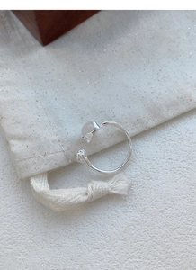 Detail of S925 silver ring with chalcedony bud design on beige linen jewelry bag