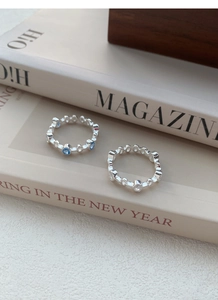 Close-up of S925 silver hollow chain rings with blue and clear zircon on a magazine