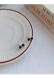 Detail of silver bow earrings with black heart stones on vintage ceramic dish