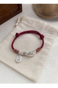 Gros plan d'un bracelet tressé rouge avec chat en argent et breloque porte-bonheur