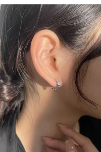 Détail d'une boucle d'oreille en argent à maillons avec zircon bleu portée par un mannequin