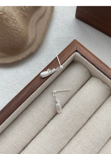 Macro view of teardrop earrings with brushed silver texture and tiny zircon inlay