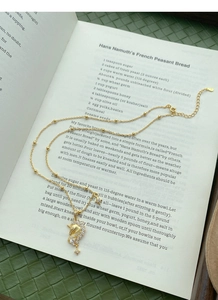 Détail d'un collier licorne dorée orné de zircons sur une page de livre ancienne