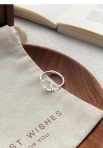 Macro detail of silver rocking horse ring on beige gift bag and wooden tray decor