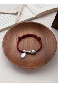 Gros plan du bracelet en corde rouge tressée avec pendentif chat porte-bonheur en argent
