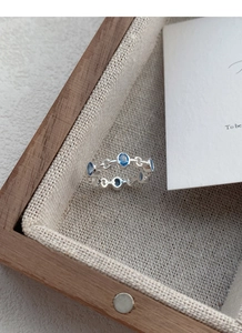 Detailed shot of S925 silver hollow ring with oval blue zircons in a wooden gift box