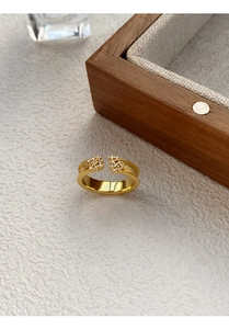 Detail of gold vintage ring with milgrain edges and star-shaped zircon clusters on wood