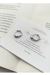 Détail des boucles d'oreilles en argent torsadé avec pierre carrée bleue sur carte