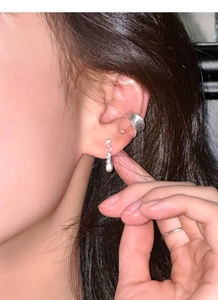 Close-up of matte brushed silver ear cuff and teardrop zircon pendant earrings