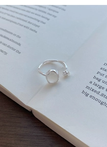 Detail of S925 silver ring with white chalcedony bud on an open book background
