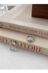 Détail de créoles chaîne en argent avec zircon bleu carré sur des livres vintage