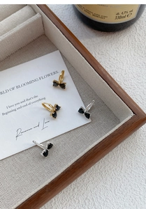 Close-up of bow-shaped earrings with heart-cut black stones in gold and silver finish
