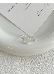 Macro detail of S925 silver ring with white chalcedony bud on a white ceramic tray