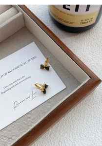 Detail of gold-plated hoop earrings featuring black zircon heart-shaped bow pendants