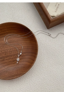 Detailed view of S999 silver star necklace with zircons resting in a wooden bowl
