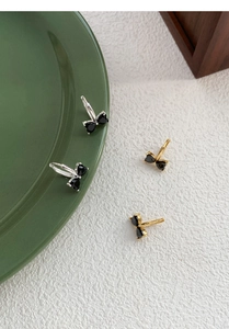 Macro detail of S925 silver bow-shaped earrings with black heart-shaped zircon stones