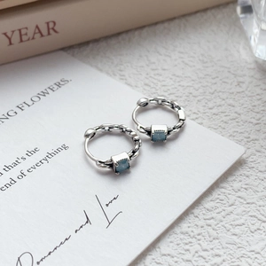 Boucles d'oreilles créoles S999 en argent avec zircon bleu sur carte de présentation