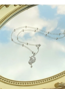 Détail macro du pendentif licorne en argent avec zircons reflété sur un fond de ciel bleu