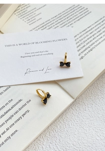 Detail of S925 silver hoop earrings with black zircon bow and elegant gold plating