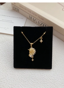 Détail du collier licorne doré avec oxydes de zirconium sur présentoir en velours noir