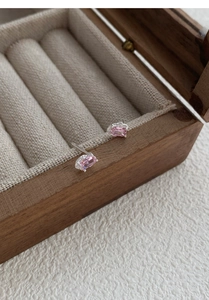 Detailed view of silver stud earrings with rectangular pink zircon in a vintage jewelry box