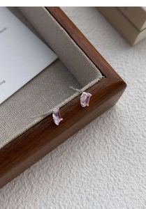 Close-up of pink rectangular zircon stud earrings with silver four-prong setting