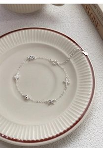 Macro shot of silver starfish shell charm bracelet with bow accents on ceramic plate