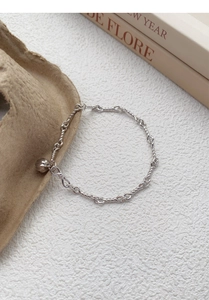 Macro shot of silver pumpkin pendant and twisted rope chain bracelet with fine metal texture