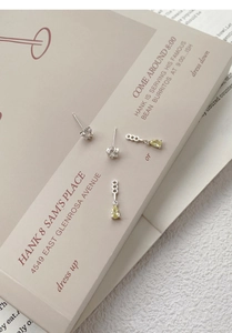 Detail of S925 silver star and teardrop zircon earrings set on a stylish magazine background