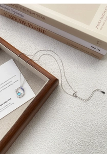 Détail d'une chaîne en argent S925 avec pendentif pierre de lune sur plateau bois