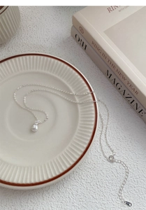 Détail du pendentif sac de chance en argent S999 posé sur une assiette vintage