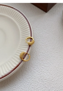 Détail de créoles en argent S925 dorées 18K avec perle dépolie sur assiette céramique