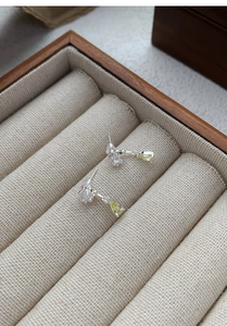 Detail showing S925 silver star earrings with yellow teardrop zircon in a wooden box