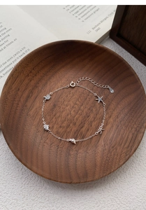 Macro detail of S925 silver ocean-themed bracelet with starfish and shell charms